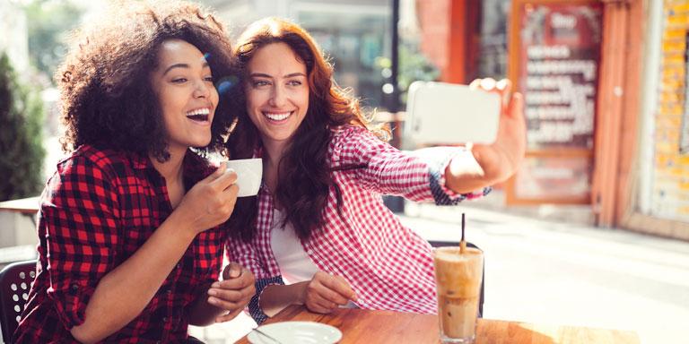 Two women having coffee and taking a selfie.